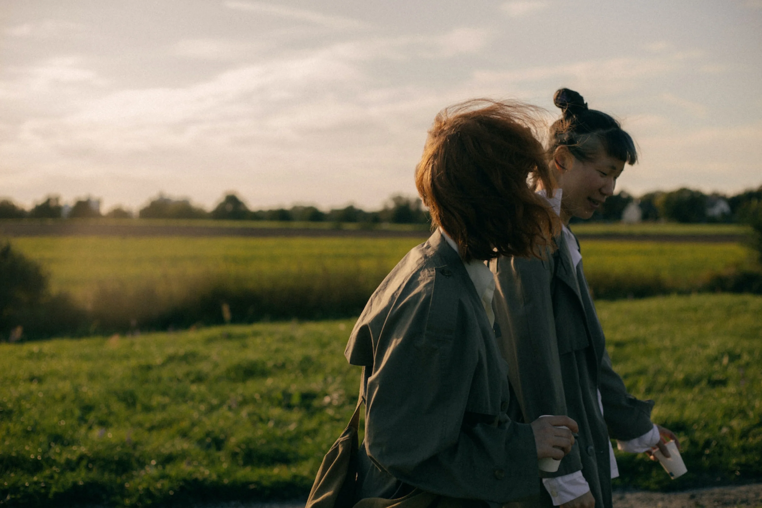 two people walking through a grassy field